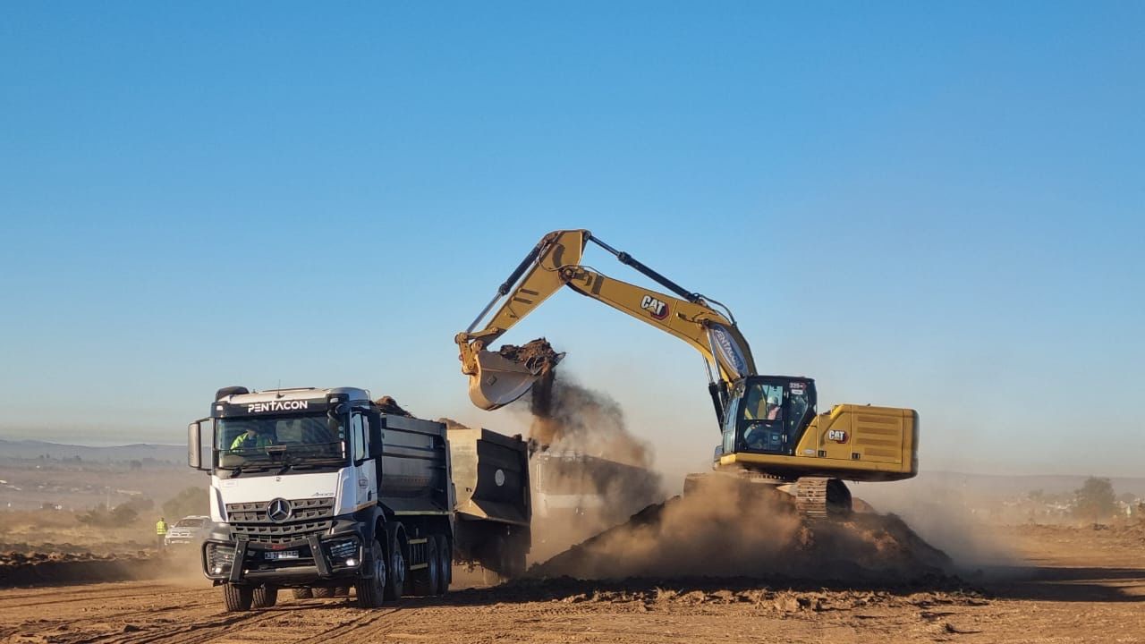 Excavator loading soil into a tipper truck on a Namibian construction site